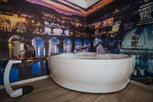 Hotel Seven Rooms في ميلانو: حمام مع حوض استحمام أمام جدارية