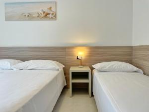 two beds in a room with a side table with a lamp at Villa Ivona in Bibione