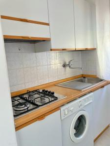 a kitchen with a stove and a washing machine at Villa Ivona in Bibione