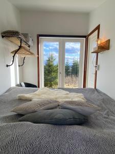 1 dormitorio con 1 cama y ventana grande en Cozy forest cabin with amazing mountain view en Torsby