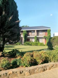a building with a yard with bushes and a tree at Naleli Guest House in Selomas