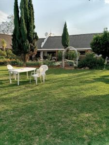 two white chairs and a table in the grass at Naleli Guest House in Selomas