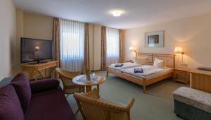 a hotel room with a bed and a couch at Hotel am Wariner See in Warin