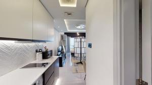 a white kitchen with a sink and a hallway at Key View - Lake View in Dubai