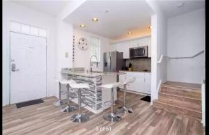 Una cocina con gabinetes blancos y una isla de cocina con taburetes de bar. en Orlando House, en Kissimmee
