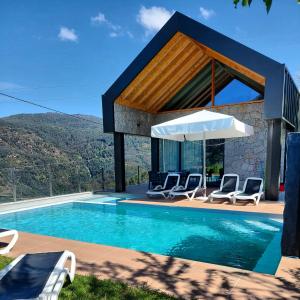 a house with a swimming pool with chairs and an umbrella at Casas do Bau in Vieira do Minho