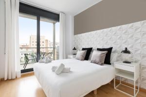 a white bedroom with a large bed and a large window at chicStays Apartment Ciutadella Park in Barcelona