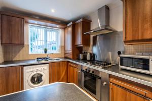 a kitchen with wooden cabinets and a washer and dryer at Large Family Property & Central Location & Free Parking in Armthorpe