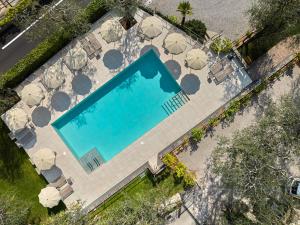 an overhead view of a swimming pool with tables and umbrellas at Hotel Rosemarie in Limone sul Garda
