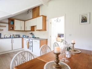 eine Küche mit weißen Schränken und einem Holztisch in der Unterkunft Menai View in Y Felinheli