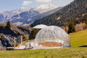 Lumbrein的住宿－Bubble-Suite mit wunderschönem Blick，山丘上的圆顶房屋,背景是群山