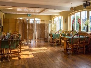 uma sala de jantar com mesas, cadeiras e janelas em The Castle Hotel em Talgarth