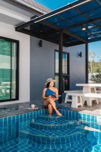 a woman sitting next to a swimming pool at Arthur Pool Villa Chaam 3BR with Iconic Mountain view Pet & Family Friendly in Ban Phu Wai