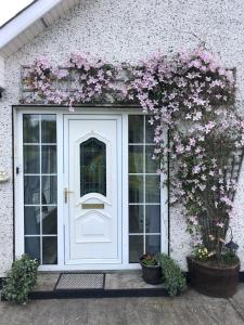 una porta bianca con fiori su un edificio di Lough Aduff Lodge 5 minutes from Carrick on Shannon a Leitrim