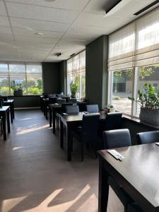 a dining room with tables and chairs and windows at Gasterij De Koekoekshof in Elp