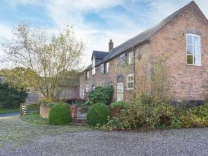 una gran casa de ladrillo con una ventana y arbustos en The Coach House, en Tilston