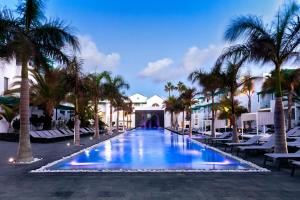 a resort swimming pool with palm trees and lounge chairs at Barceló Teguise Beach - Adults Only in Costa Teguise