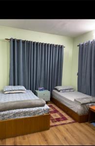 2 Betten in einem Zimmer mit blauen Vorhängen in der Unterkunft Welcome Home Bhaisepati in Pātan