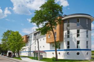 ein weißes Gebäude mit einem Baum davor in der Unterkunft Apartament Pod Żaglami in Zegrze Południowe