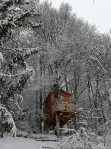 uma casa na árvore de madeira numa floresta coberta de neve em Cabane du Druide Domaine de Fangorn em Glux