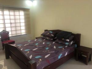 um quarto com uma cama, uma cadeira e uma janela em Tagaytay BNR Guesthouse 4BR With Balcony 12-14 Guest em Tagaytay