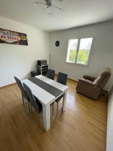 APPARTEMENT LE DOMAINE DES LIBELLULES PROCHE WALIBI في Corbelin: غرفة معيشة مع طاولة وكراسي وأريكة