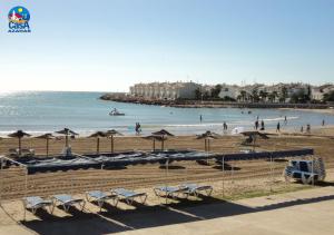 a beach with chairs and umbrellas and people in the water at Apartamentos Madeira Casa Azahar in Alcossebre