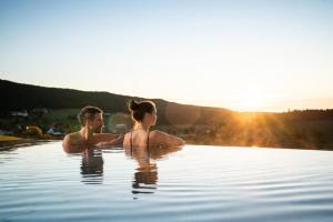 Ein Mann und eine Frau sitzen im Wasser im Pool in der Unterkunft Hotel Saigerhöh Wellness Spa Golf Wandern über dem Titisee in Lenzkirch + 37 Fotos