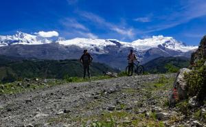 two people riding bikes on a dirt road with snow covered mountains at Taulli Guest in Marcará