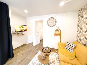 een woonkamer met een bank en een klok aan de muur bij Le numéro 12 Netflix Wifi in Cherbourg en Cotentin