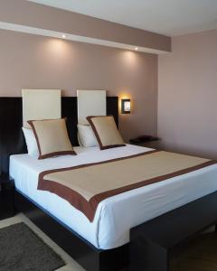 een slaapkamer met een groot bed met witte lakens en kussens bij Café de Rome in Dakar