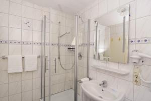 ein weißes Bad mit einer Dusche und einem Waschbecken in der Unterkunft Hotel Klostermühle Siebenborn in Maring-Noviand