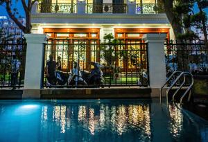 a house with a swimming pool in front of a building at Tan Truong Son Legacy Hotel in Sầm Sơn