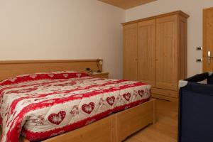 um quarto com uma cama com uma colcha vermelha e branca em Agritur Maso Rauter em Vattaro