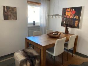 uma sala de jantar com uma mesa de madeira e cadeiras brancas em Haus VALLESIA em Saas-Fee