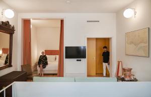 two men standing in a living room with a television at Cais Urban Lodge in Lisbon