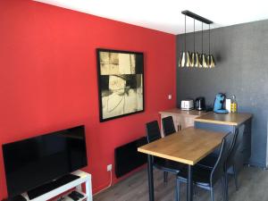 a dining room with red walls and a table and a television at Très bel appartement vue mer avec piscine in Douarnenez