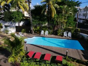 a pool with chaise lounge chairs and a resort at Les Cerisiers-Beach Apartment with Pool, Centrally Located in Flic-en-Flac in Flic-en-Flac