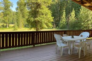 Private 2-Acre Retreat with MTN Views, Walk to River في Saint Maries: طاولة بيضاء وكراسي على سطح خشبي