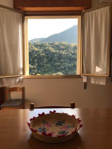 uma tigela sentada numa mesa em frente a uma janela em La Corbula - Casa Vacanze - Q5992 em Fluminimaggiore