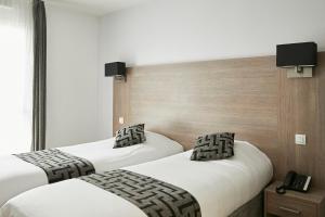1 dormitorio con 2 camas y teléfono. en Tulip Inn Massy Palaiseau - Residence, en Palaiseau
