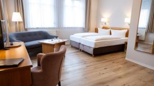 ein Hotelzimmer mit einem Bett und einem Sofa in der Unterkunft Pension Sellent in Stendal