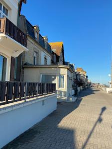 an empty street with buildings and a fence at Aux Bains des Mots in Saint-Aubin-sur-Mer