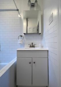 a white bathroom with a sink and a mirror at 1BR Apt in Sunnyside 15 min to Manhattan in Woodside