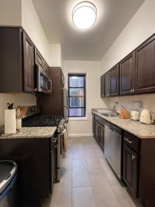 a large kitchen with black cabinets and a sink at 1BR Apt in Sunnyside 15 min to Manhattan in Woodside