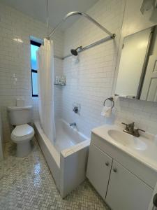 a bathroom with a toilet and a tub and a sink at 1BR Apt in Sunnyside 15 min to Manhattan in Woodside