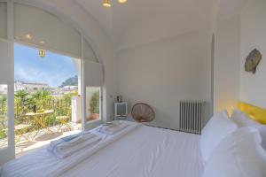 a white bedroom with a large bed and a balcony at Villa Dorothee in Capri