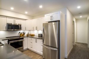 a kitchen with white cabinets and a stainless steel refrigerator at Magog Condo by Revelstoke Vacations in Revelstoke