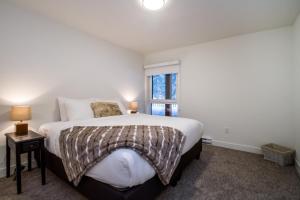 a bedroom with a large bed and a window at Magog Condo by Revelstoke Vacations in Revelstoke