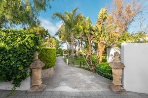 Una pasarela en una villa con árboles y una valla en Suites Cortijo Fontanilla, en Conil de la Frontera